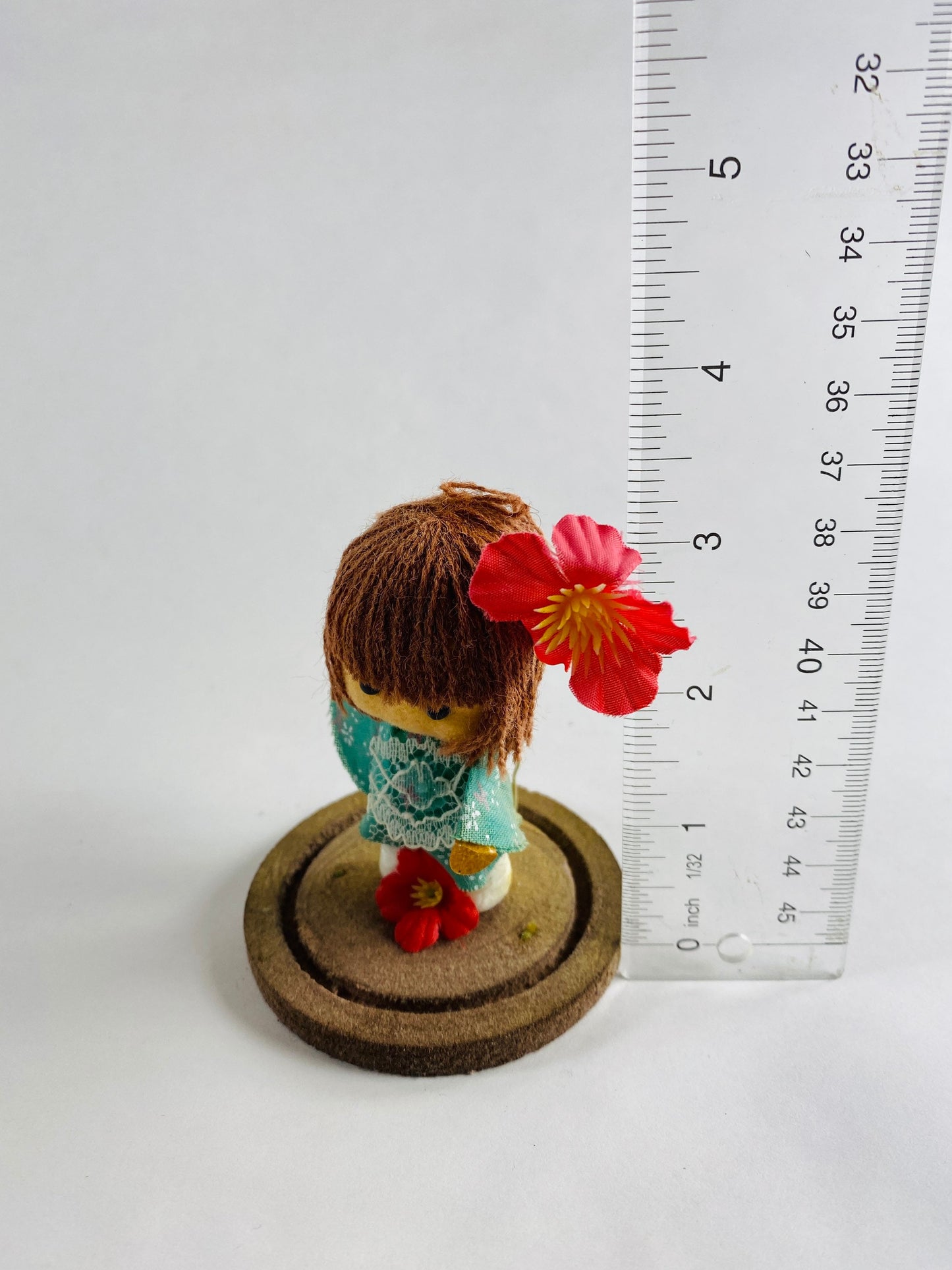 Vintage doll circa 1960s sad eyes felt girl long brown hair and pink orchid attached to round base Small home bookshelf decor hula souvenir